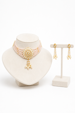 A gold and pearl jewelry set. The set includes a multi-strand pearl choker necklace with a large gold floral medallion and dangling pearl accents, along with matching gold and pearl dangle earrings.