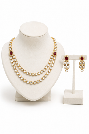 A gold-tone jewelry set featuring a double-strand pearl necklace with red gemstone accents and matching drop earrings.