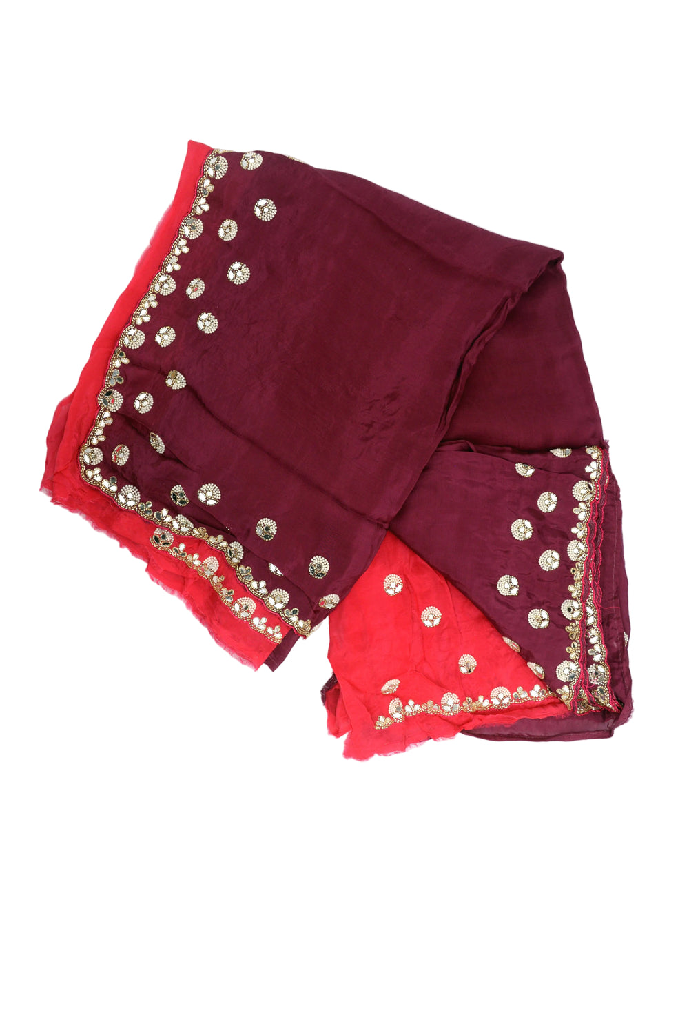A woman models a deep maroon purple saree with a red blouse, decorated with gold mirror work and a red border, set against a solid brown studio backdrop.