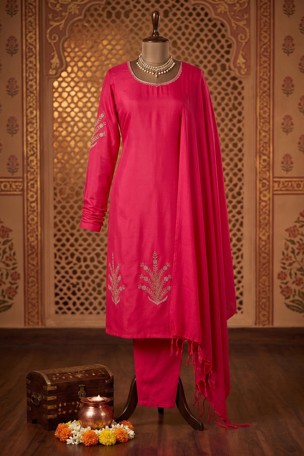 A bright pink traditional Indian salwar kameez suit, featuring a long kurta with silver embroidery, matching pants, and a draped dupatta.