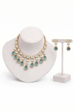 Gold-tone statement necklace and matching drop earrings with light blue teardrop stones.