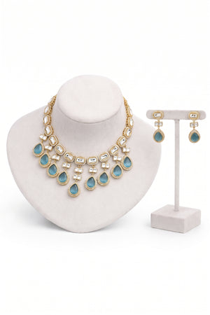 Gold-tone statement necklace and matching drop earrings with light blue teardrop stones.