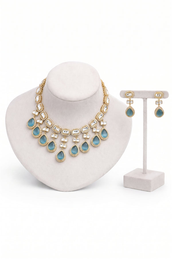 Gold-tone statement necklace and matching drop earrings with light blue teardrop stones.