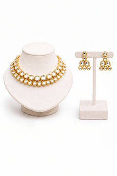 Gold jewelry set featuring a double-strand necklace and matching earrings with clear stones.