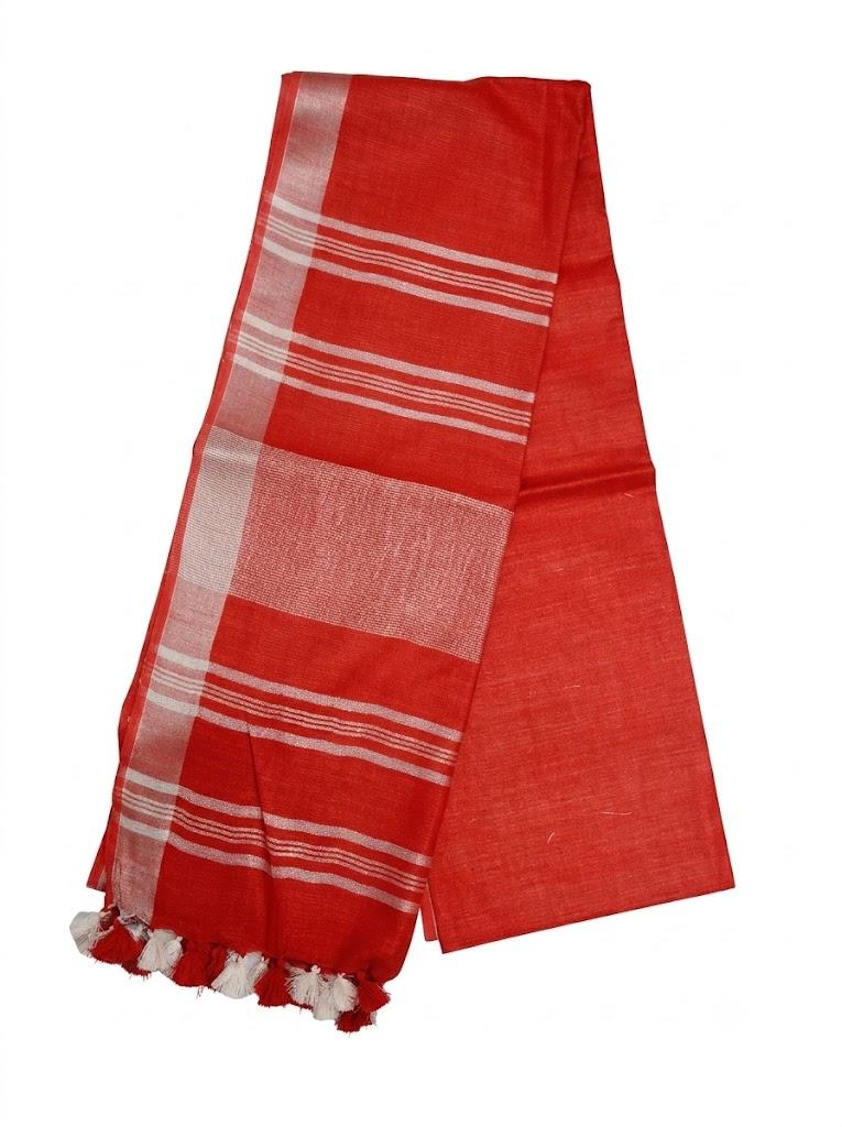 A woman models a bright red saree with white striped borders in an ornate indoor setting with traditional decor.