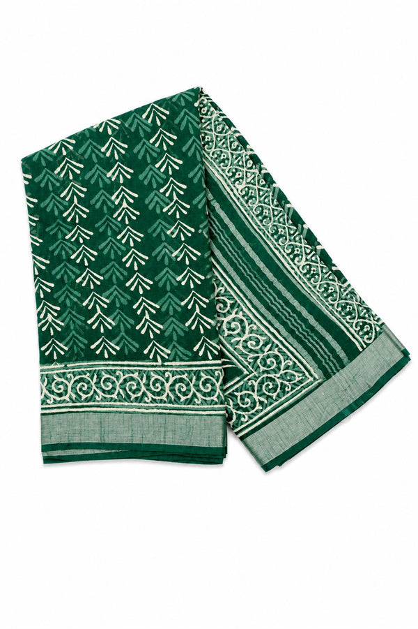 A folded green saree with white printed patterns, including a repeating chevron motif and an ornate border design.